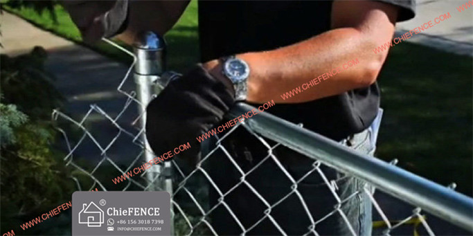 Without releasing the fence puller, insert a tension bar in the mesh close enough so it can be fastened to the tension bands on the end post nearest the fence puller.
To remove the excess mesh between the tension bars and end post, open a loop at the top and bottom, then twist and pull the strand free.